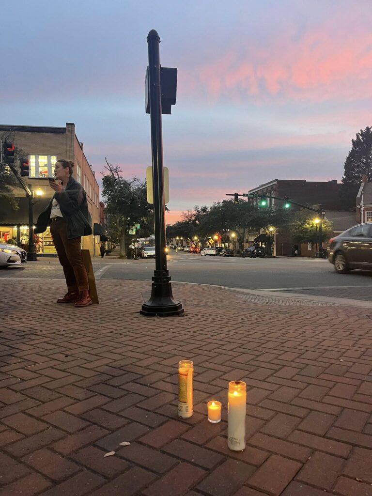 Three candles burn in a vigil honoring Renee Nicole Good on the corner of Washington and Dekalb in Shelby, NC. 