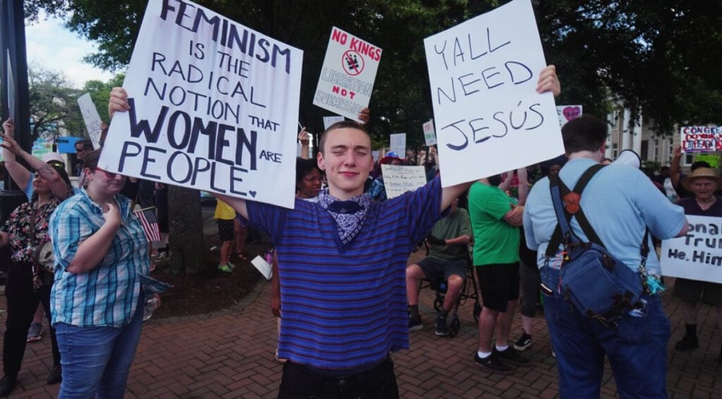 A young man holds protest signs at a gathering on the square in Shelby, NC